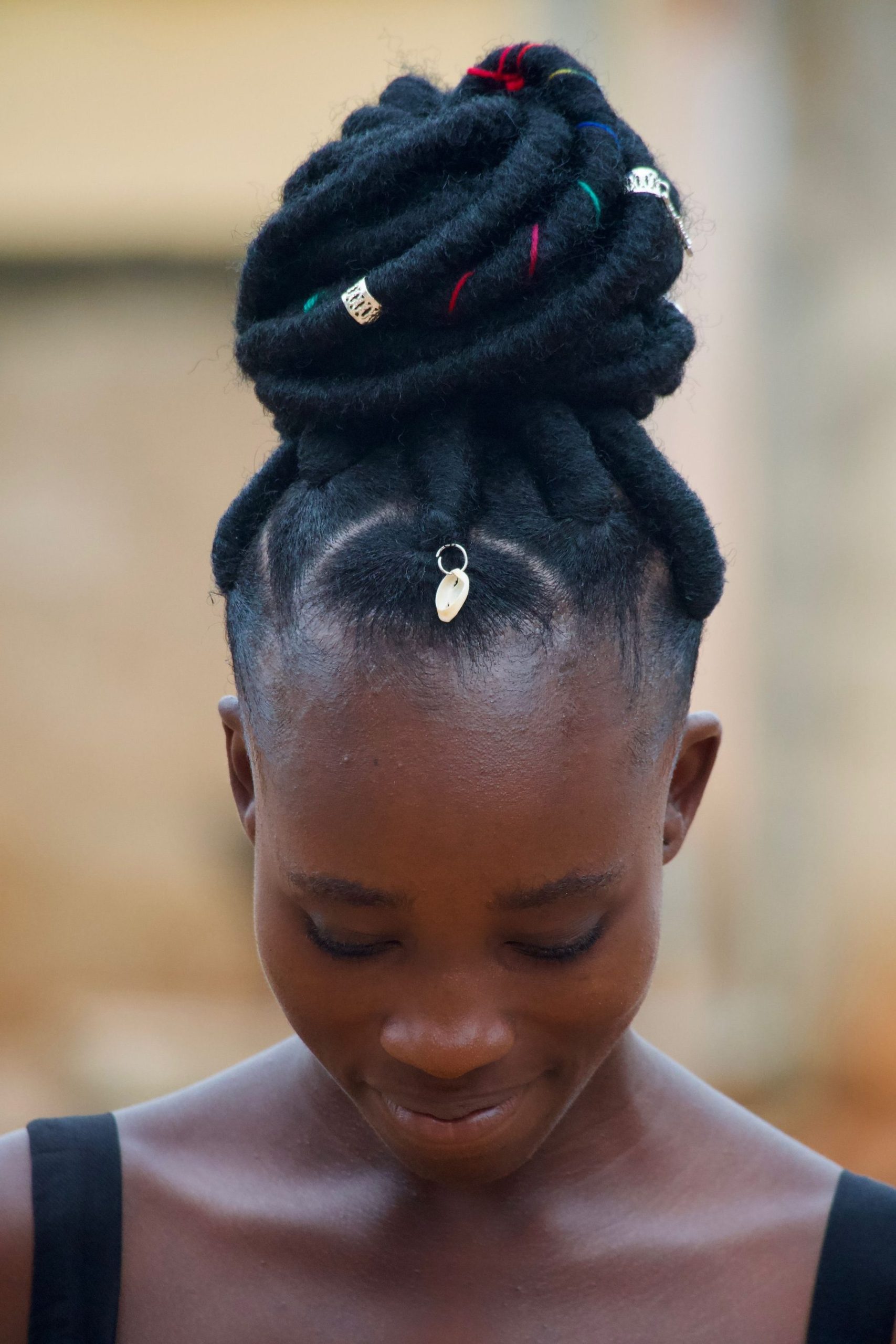 Femme aux cheveux crépus coiffés en locks relevées en chignon, ligne des cheveux visible sur le front et les tempes