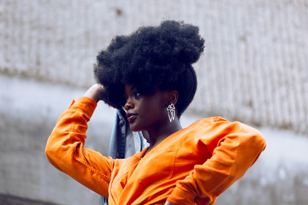 femme avec un afro puff volumineux, la main dans les cheveux