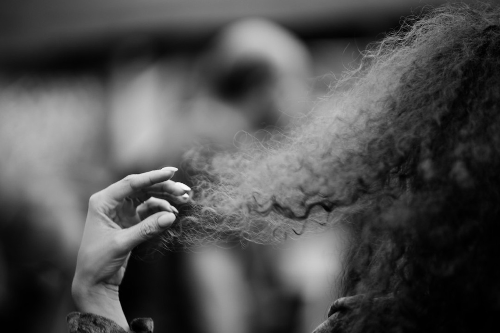 Femme appliquant une brume parfumée sur des cheveux afro, à distance des pointes