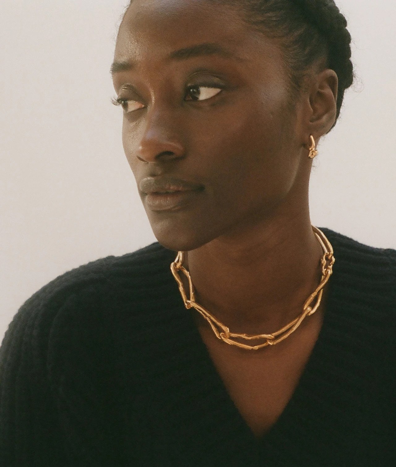 Portrait d'une femme portant un collier doré à chaînons et des boucles d'oreilles